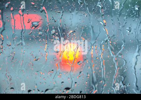 Image floue de la circulation à travers une fenêtre de voiture pendant la forte pluie.verre de voiture avec beaucoup de gouttes de pluie pendant la douche de pluie.vue de la ville par la fenêtre floue Banque D'Images