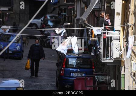 Naples, Italie. 08 avril 2020. Un homme avec son enfant est sur le balcon comme un homme portant un masque de protection passe dans la rue dans le quartier espagnol (quartier Spagnoli) dans le centre-ville. En Italie, le maintien continue le décret gouvernemental déclarant à toute l'Italie une zone protégée pour lutter contre l'infection au coronavirus, fermer les écoles, les bureaux publics et les magasins. Crédit: Independent photo Agency SRL/Alay Live News Banque D'Images