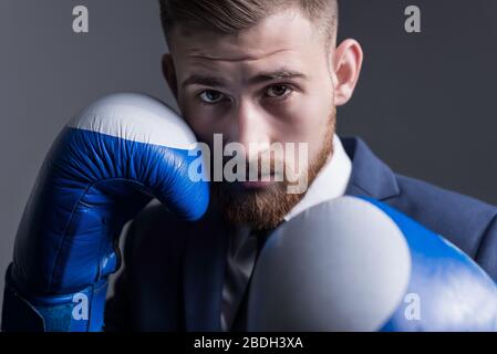 plan principal, studio portrait dramatique d'un jeune homme barbu de vingt-cinq ans, un homme en costume d'affaires, regardant l'appareil photo, tenant Banque D'Images