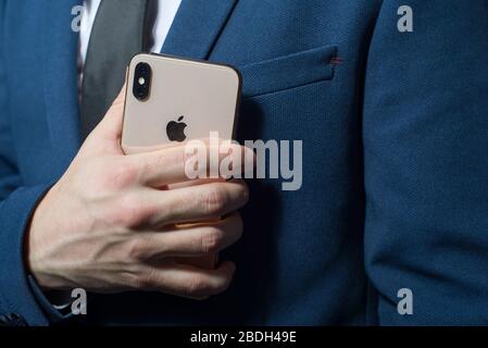 Zaporozhye. Ukraine. Février 2020. Gros plan portrait d'un jeune homme barbu dans un costume d'affaires tenant un iPhone XS dans sa main. Nouveau smartphone de Banque D'Images