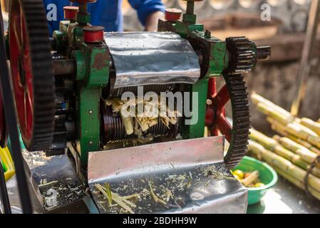 Vendeur de rue en Inde, en extrayant du jus de canne à sucre à partir de sugarcanes à l'aide d'une presse-fruits Banque D'Images