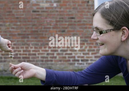 La mère et l'enfant sourit et jouent avec des fleurs de Marguerite dans le jardin à la maison pendant la période d'auto-isolement - 2020 COVID-19 pandémie de coronavirus Banque D'Images