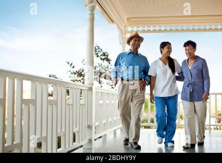 Infirmière marchant avec un couple senior sur la terrasse de la maison de repos. Banque D'Images