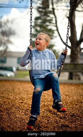 Jeune garçon jouant sur une balançoire dans un parc. Banque D'Images