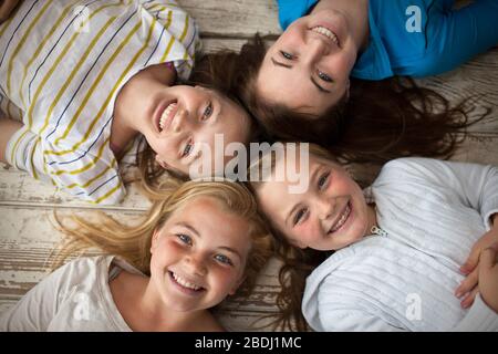 Portrait de quatre sœurs souriantes couchées sur le sol avec leurs têtes ensemble. Banque D'Images