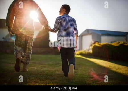 Mid adult man vêtu d'un uniforme militaire est accueilli par son fils. Banque D'Images