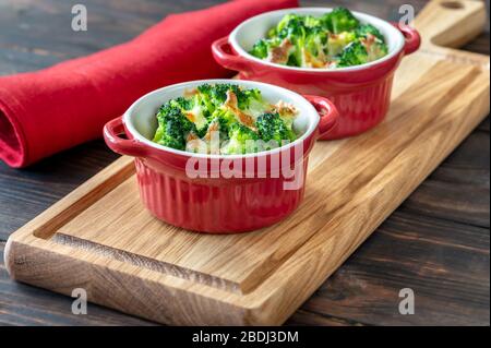 Deux pots de brocoli cuit au four et fromage sur planche en bois Banque D'Images