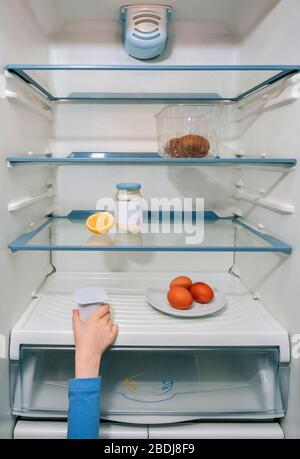 Une fille prend le dernier yaourt du réfrigérateur Banque D'Images