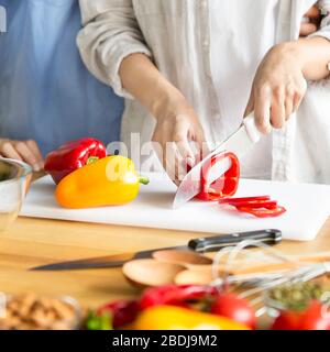 Gros plan de la femme coupant le paprika rouge sur les tranches Banque D'Images