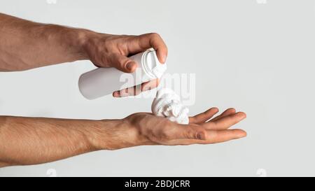 Homme inconnu appliquant de la mousse de rasage du biberon sur la main, fond blanc. Panorama Banque D'Images