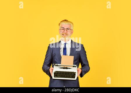 Les vieux habitudes de l'auteur de bâton. Les hommes d'affaires utilisent la technologie rétro. Homme mûr teint les cheveux de barbe fond jaune. Magasin de marchandises d'occasion. Objets anciens du vendeur. Connaisseur des valeurs vintage. Machine à écrire vintage. Banque D'Images