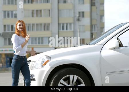 Yong jolie femme debout près d'une grande voiture tout terrain à l'extérieur. Fille du pilote dans les tenues de l'extérieur de son véhicule. Banque D'Images