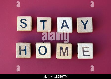 L'inscription reste à la maison vue dessus sur un fond rouge. Temps de quarantaine pendant le virus corona. Cubes en bois avec lettres. Isolement de tout le monde du Banque D'Images