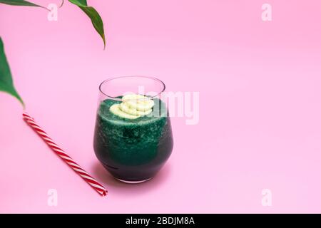 Smoothie banane spiruline dans une tasse en verre sur fond rose, espace de copie Banque D'Images