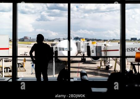 Un passager regarde les opérations aéroportuaires depuis un salon de départ de l'aéroport international Pearson de Toronto, Canada. Banque D'Images