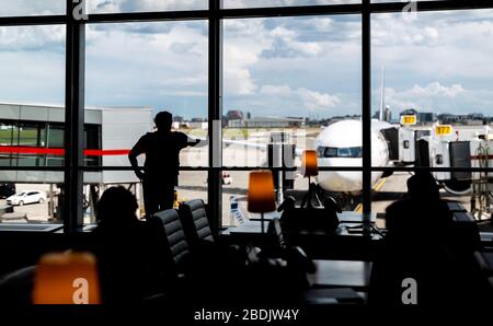 Un passager regarde les opérations aéroportuaires depuis un salon de départ de l'aéroport international Pearson de Toronto, Canada. Banque D'Images