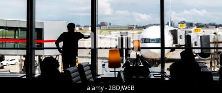 Un passager regarde les opérations aéroportuaires depuis un salon de départ de l'aéroport international Pearson de Toronto, Canada. Banque D'Images