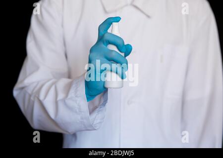 Vue rapprochée des mains du médecin montrant un antiseptique ou un désinfectant personnel. Mesures de protection de Covid-19. Médecin en robe blanche à fond blanc propre. Banque D'Images