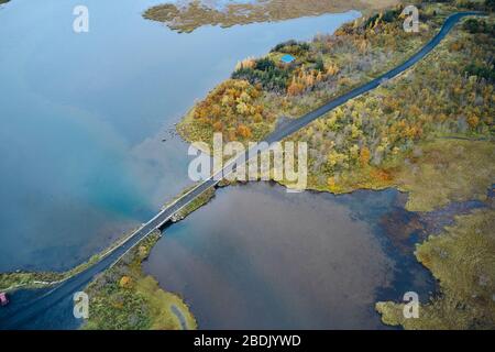 Vue sur la route asphaltée droite reliant les rives d'une zone humide paisible le jour d'automne en Islande Banque D'Images