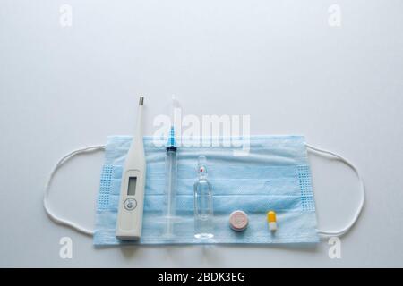 masque médical sur fond cyan, bleu.masque de visage. masque pour maladies. Thermomètre et médicament. Image faciale jetable. Bandage respiratoire médical visage. Concept de quarantaine du coronavirus. Banque D'Images