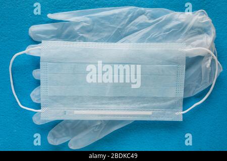 Une paire de gants en latex médical bleu fin et un écran facial sur fond blanc. Gants médicaux jetables en caoutchouc et masque. Sujets de protection. Recours. Banque D'Images