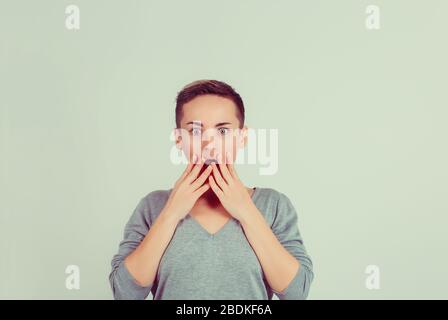 Une femme stupéfiée qui regarde les mains de l'appareil photo sur un mur de fond vert isolé à bouche ouverte. Langage corporel émotion humaine expression visage studio tir hor Banque D'Images