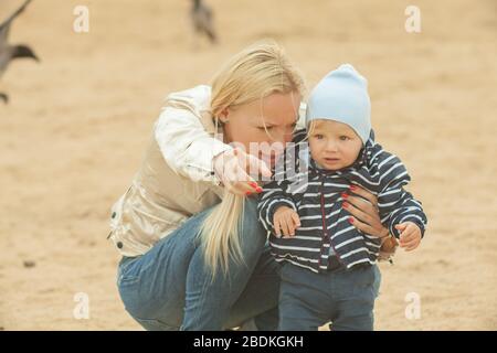 Une mère avec de longs cheveux maintient doucement son petit fils dans ses bras. Photo dans le parc avec lumière naturelle Banque D'Images