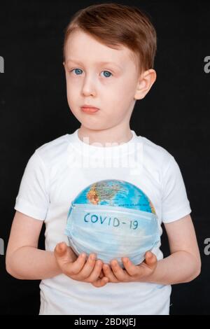 Kid in Self isolation regarder le globe apprendre à propos de Covid-19 Coronavirus de la maison, enfant avec un visage curieux pensant à la planète pendant le verrouillage covid vers le bas, quarantaine et social distancing concept Banque D'Images