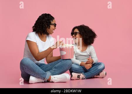 Joyeux afro maman et fille dans des verres en relief mangeant le pop-corn Banque D'Images