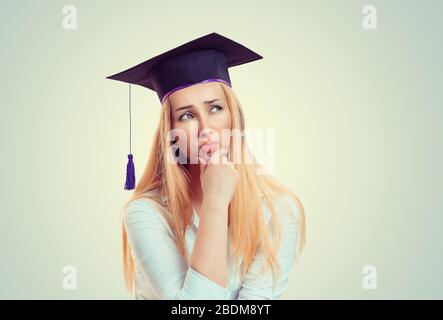 Portrait closeup jeune belle pensive étudiant diplômé diplômé diplômé jeune femme dans la robe de capuchon à la recherche pensée isolé mur jaune vert bac Banque D'Images