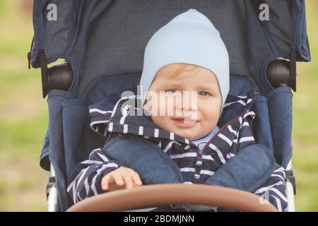 Une mère avec de longs cheveux maintient doucement son petit fils dans ses bras. Photo dans le parc avec lumière naturelle Banque D'Images