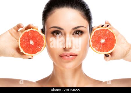 Concept de nourriture saine. Belle jeune femme tenant une pièce de pamplemousse près du visage, isolée sur fond blanc Banque D'Images