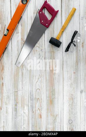 L'équipement pour le travail du bois est bien organisé sur le plancher de bois. Commandé comme suit, niveau d'aluminium magnétique orange, scie à main rouge, maillet jaune, Banque D'Images