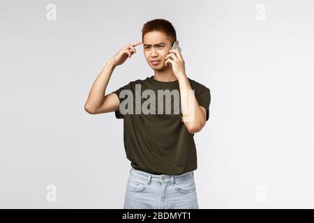 Technologie, mode de vie en ligne et concept de communication. Portrait d'un gars asiatique frustré et confus, judgmental pense que le haut-parleur est stupide ou folle Banque D'Images