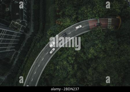 Un tir aérien de drone au-dessus de la route surélevée parmi les jungles avec le trafic à Chongqing, Chine Banque D'Images