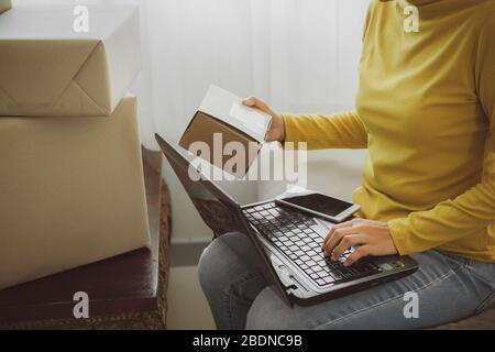 Femme tient une boîte pour préparer à livrer au client selon la commande à la maison.travail à la maison et marketing en ligne ou démarrage petite entreprise c Banque D'Images