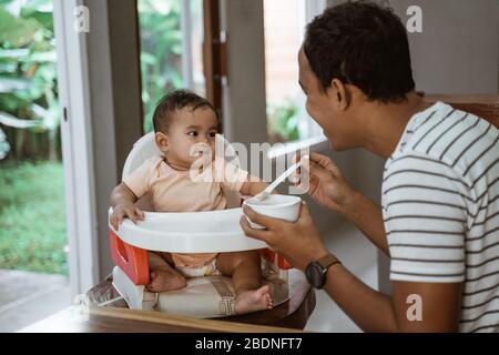 père nourrir bébé. repas homme prenant soin de sa fille Banque D'Images