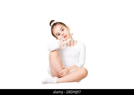 Belle petite fille brunette avec une coiffure lisse se trouve élégamment dans un léopard blanc pour la danse, regarde la caméra. Arrière-plan blanc isolé. CO Banque D'Images