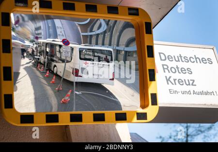 09 avril 2020, Hessen, Francfort-sur-le-Main: Le bus de la Croix-Rouge allemande (DRK), converti en centre de test mobile, peut être vu dans un miroir à l'entrée du DRK Frankfurt. Le véhicule et son personnel sont en route vers les vieilles maisons de Francfort et les maisons de soins infirmiers pour tester les résidents et le personnel du virus Corona au cours des prochains jours et semaines, soit un total d'environ 8 000 personnes. Photo: Frank Rumpenhorst/dpa Banque D'Images