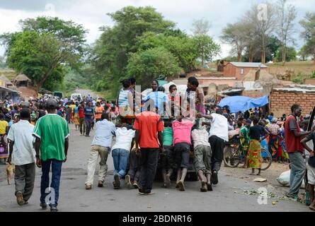 Zambie, Sinazongwe, marché rural dans le village, les hommes poussent un mini camion de panne surchargé de femmes groupe / SAMBIA, Sinazongwe Distrikt, laendlicher Markt an einer Strasse im Dorf Banque D'Images