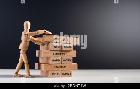 Homme en bois construire tour de longues briques en bois avec des mots. Construire votre avenir. Concept de succès, travail d'équipe, motivation, objectif de vision, A Banque D'Images