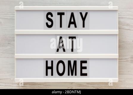 « Stay at home » dit sur un tableau moderne sur un fond blanc en bois, vue de dessus. En hauteur, par dessus, plat. Banque D'Images