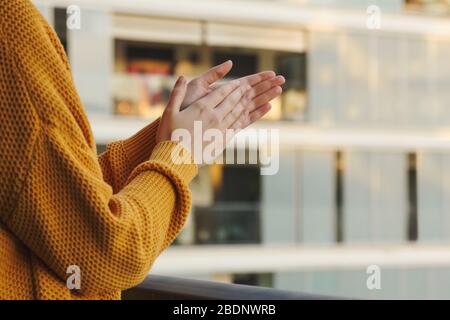 Stock photo des mains d'une fille applaudissant de son balcon pour soutenir ceux qui combattent le coronavirus Banque D'Images