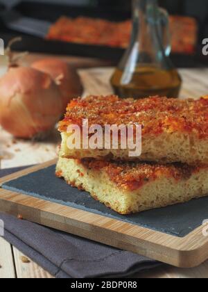 Pain italien traditionnel sicilien à pizza focaccia appelé sfincione, préparé avec des oignons, sauce tomate, anchois, fromage caciocavallo et miettes de pain Banque D'Images