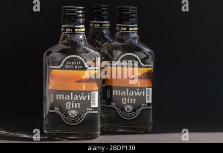 KIEV, UKRAINE - 03 AVRIL 2020: Trois bouteilles de verre de 200 ml de gin Malawi restant l'une après l'autre sur un fond sombre. Un ressortissant malawian africain Banque D'Images
