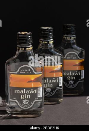 KIEV, UKRAINE - 03 AVRIL 2020: Photo verticale de trois bouteilles de verre de 200 ml de gin Malawi restant l'une après l'autre sur un fond sombre. Un national Banque D'Images