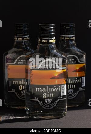 KIEV, UKRAINE - 03 AVRIL 2020: Photo verticale de trois bouteilles de verre de 200 ml de gin Malawi restant l'une après l'autre sur un fond sombre. Un national Banque D'Images