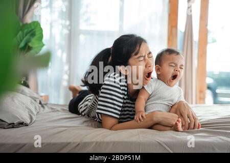 la mère et l'enfant s'ébarent ensemble tout en se posant sur le lit Banque D'Images