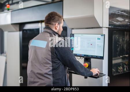 Le technicien du graveur PrintShop travaille sur un grand ordinateur d'imprimante moderne en trois dimensions avec contrôle informatique Banque D'Images