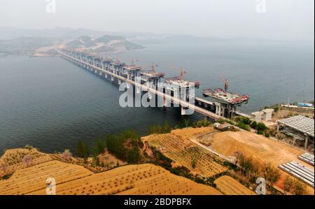 Zhengzhou. 9 avril 2020. La photo aérienne prise le 9 avril 2020 montre le chantier d'un pont de l'autoroute Mianchi-Yuanqu au-dessus de la rivière jaune, province du Henan au centre de la Chine. Le pont est une importante voie express interprovinciale reliant les provinces de Shanxi et de Henan, avec une longueur design de 1 757 mètres et une largeur de 33 mètres. Le projet devrait être achevé et ouvert au trafic d'ici la fin de 2020. Crédit: Zhu Xiang/Xinhua/Alay Live News Banque D'Images